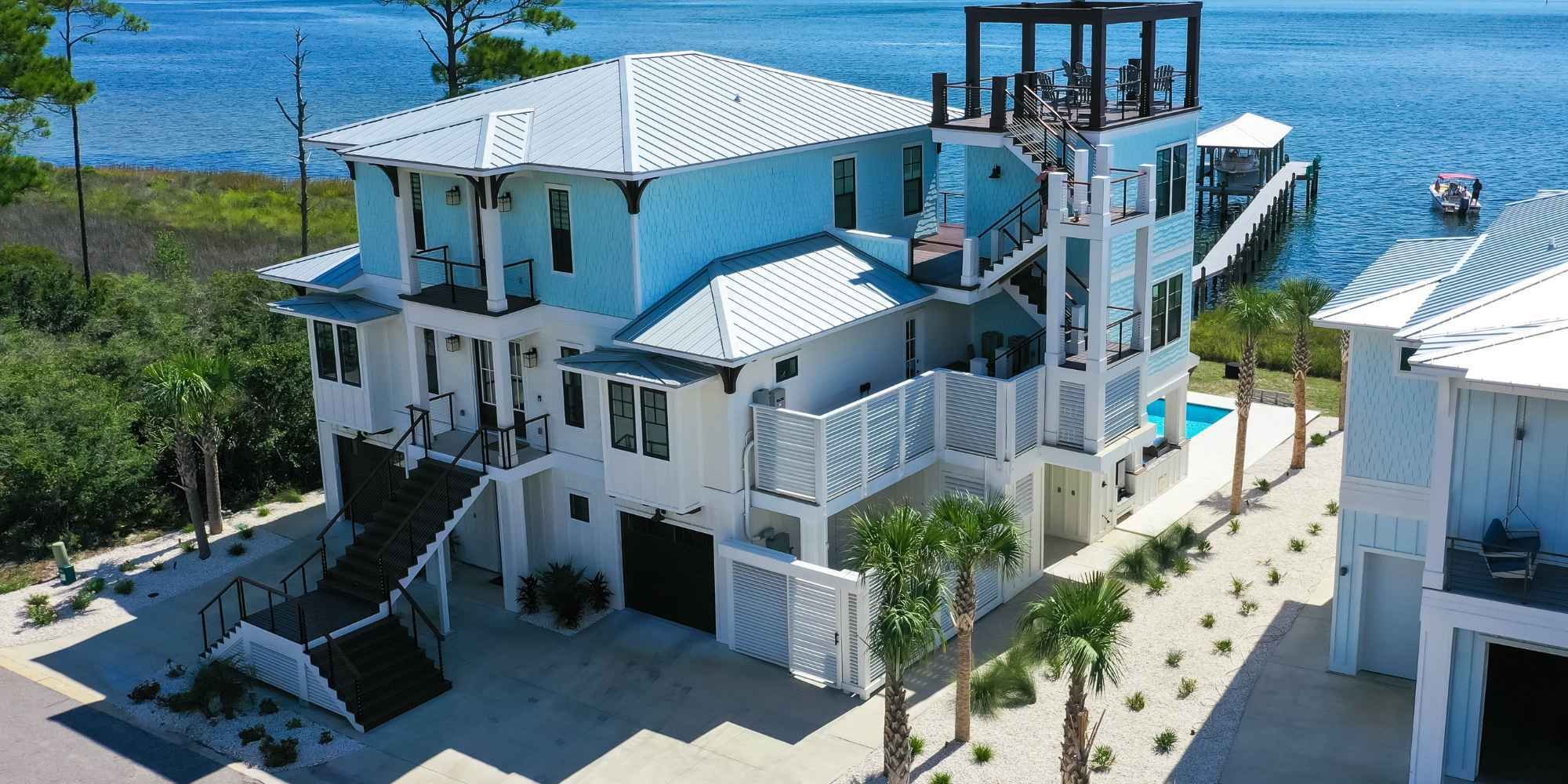 Gulf Coast waterfront piling construction custom home with a rooftop deck and a pool by Urban Infill.
