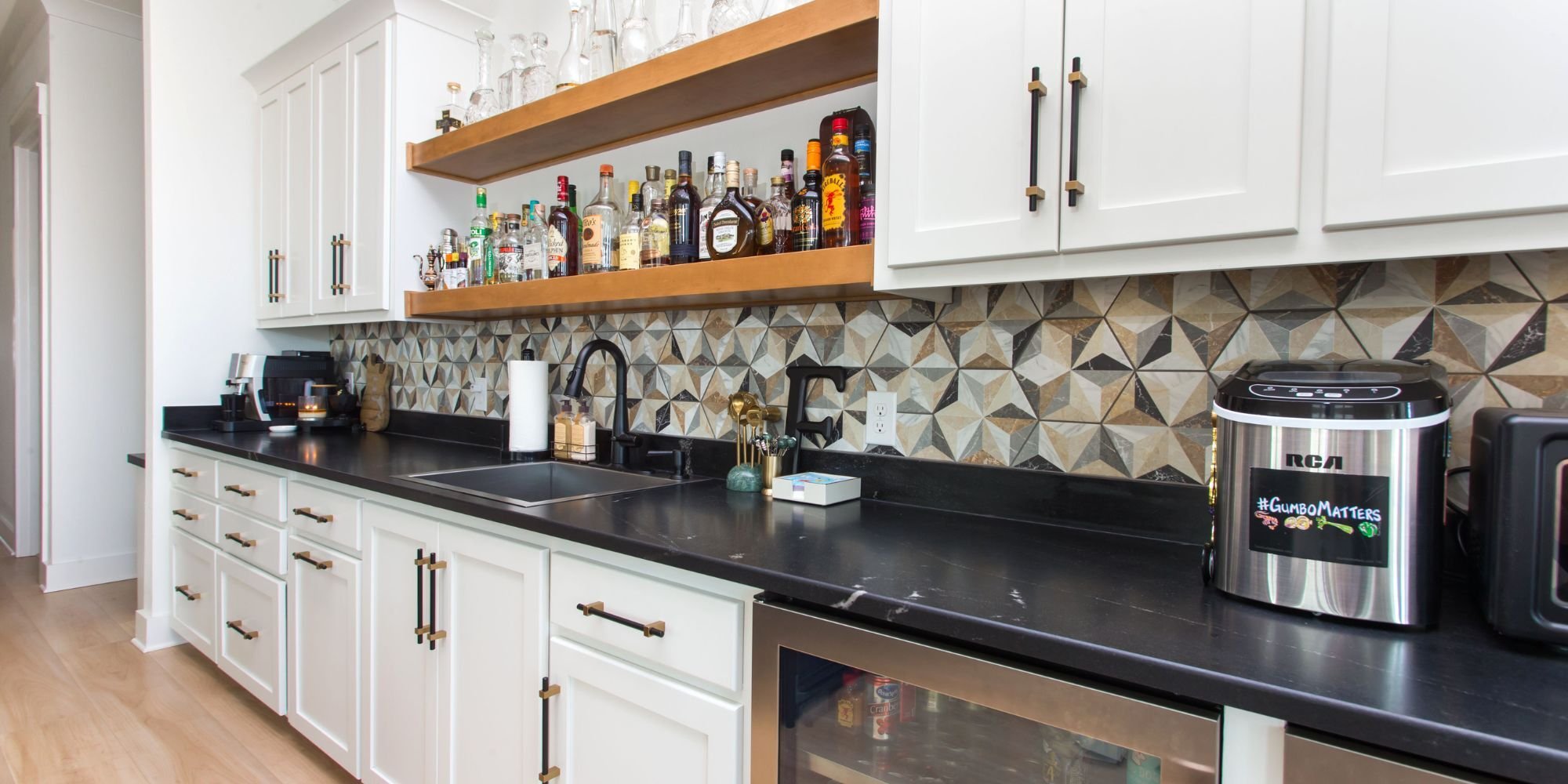 Kitchen remodel as part of a whole home remodel in Pensacola, FL, featuring black stone countertops, a liquor shelf above the sink, and a tile backsplash by Urban Infill