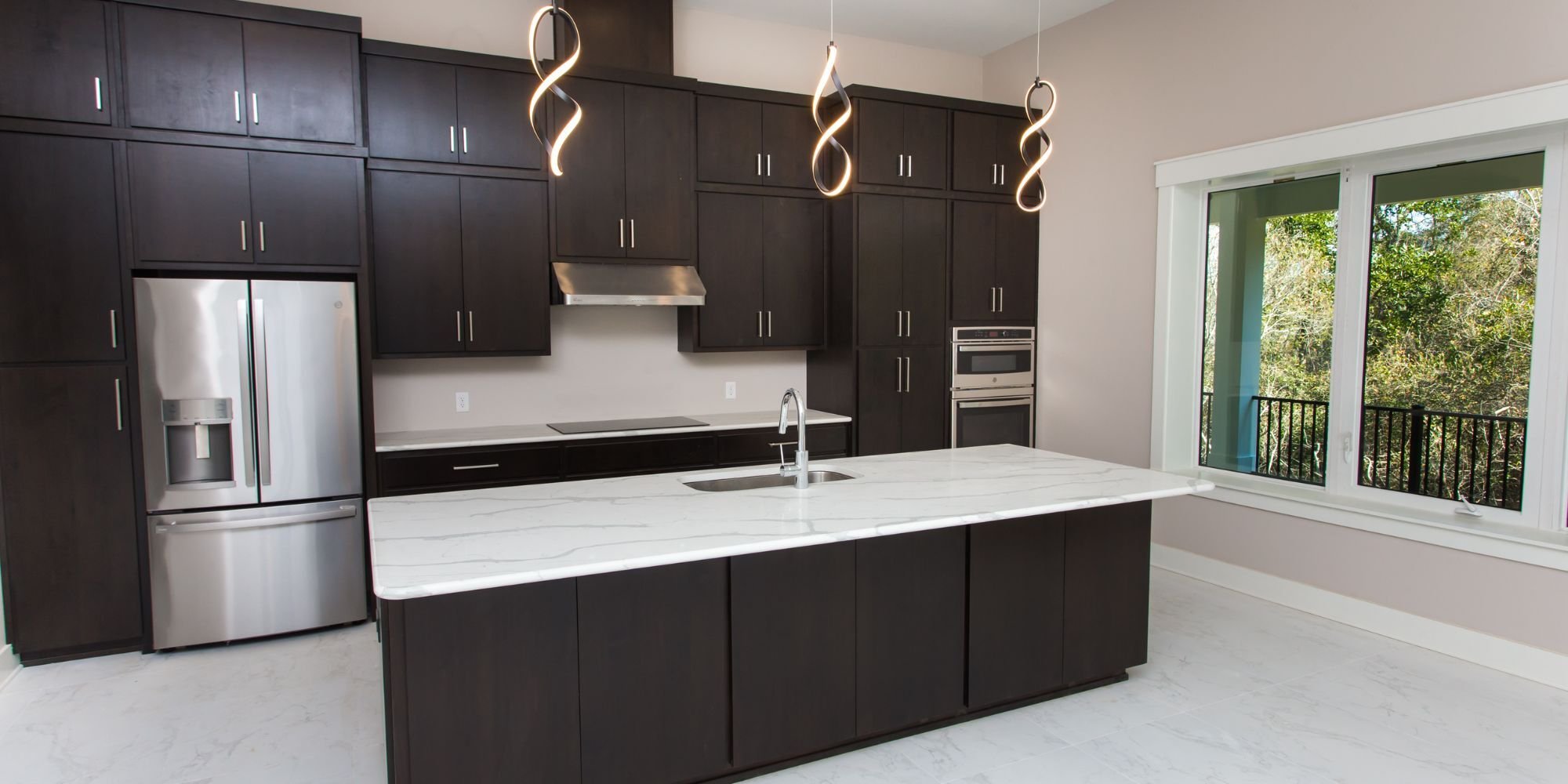 Two-tone kitchen remodel in Pensacola featuring white stone countertops, white stone tile floor, and dark brown cabinetry by Urban Infill