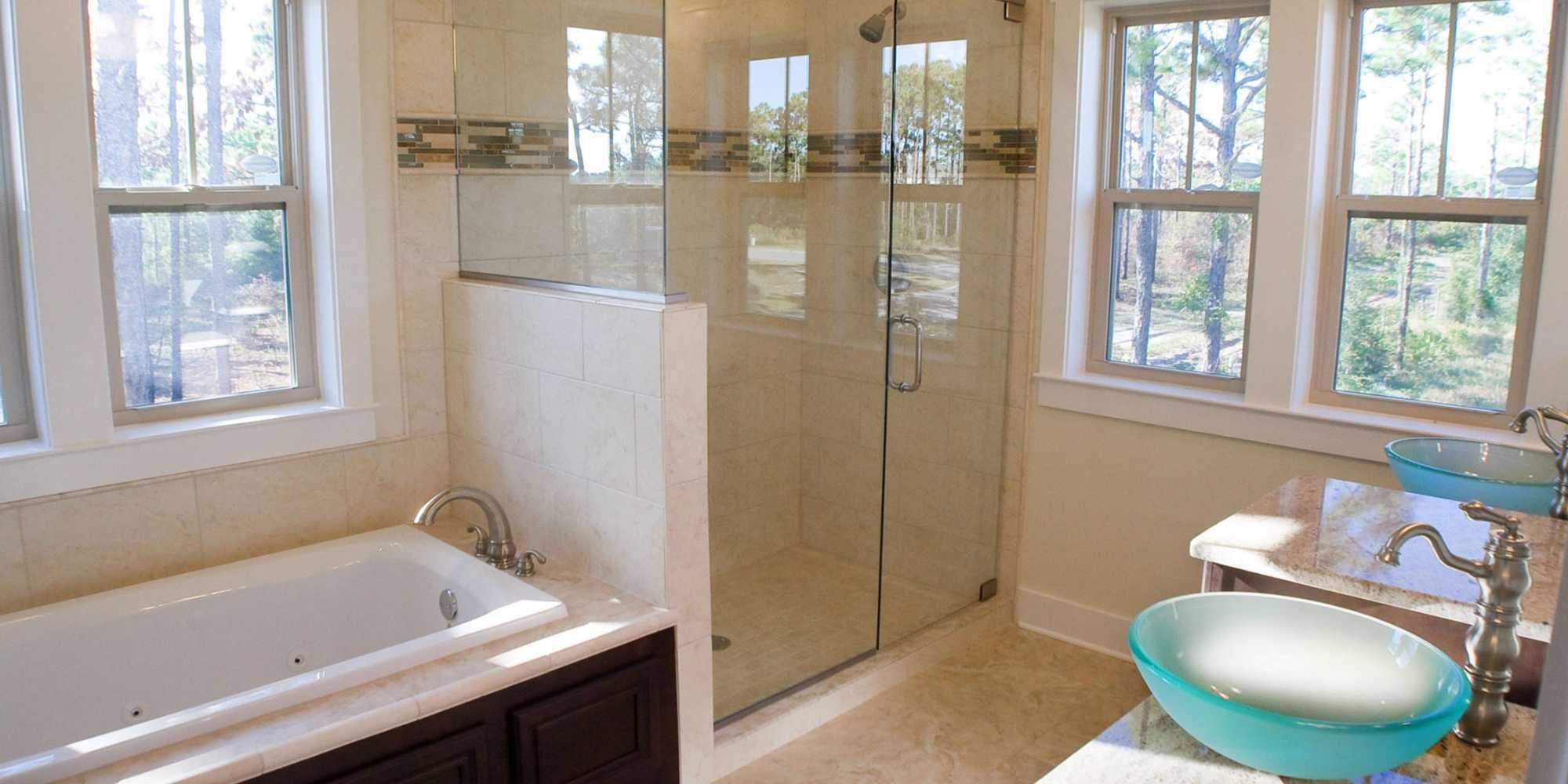 A remodeled bathroom with dual vessel sinks, a glass shower, and soaking tub in Pensacola, FL by Urban Infill