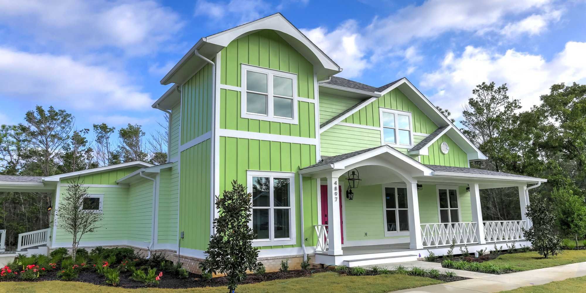 A remodeled home in Pensacola with a covered porch and bright green exterior by Urban Infill