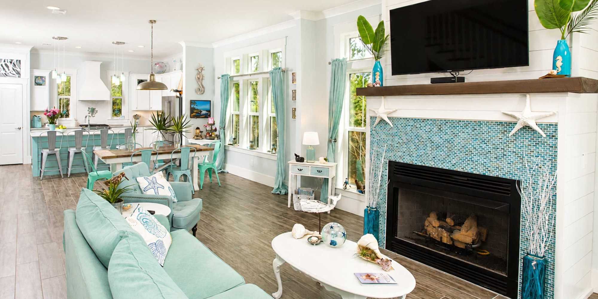 An open-concept living room and kitchen remodel with an island, separate dining table, and a fireplace by Urban Infill in Pensacola, FL