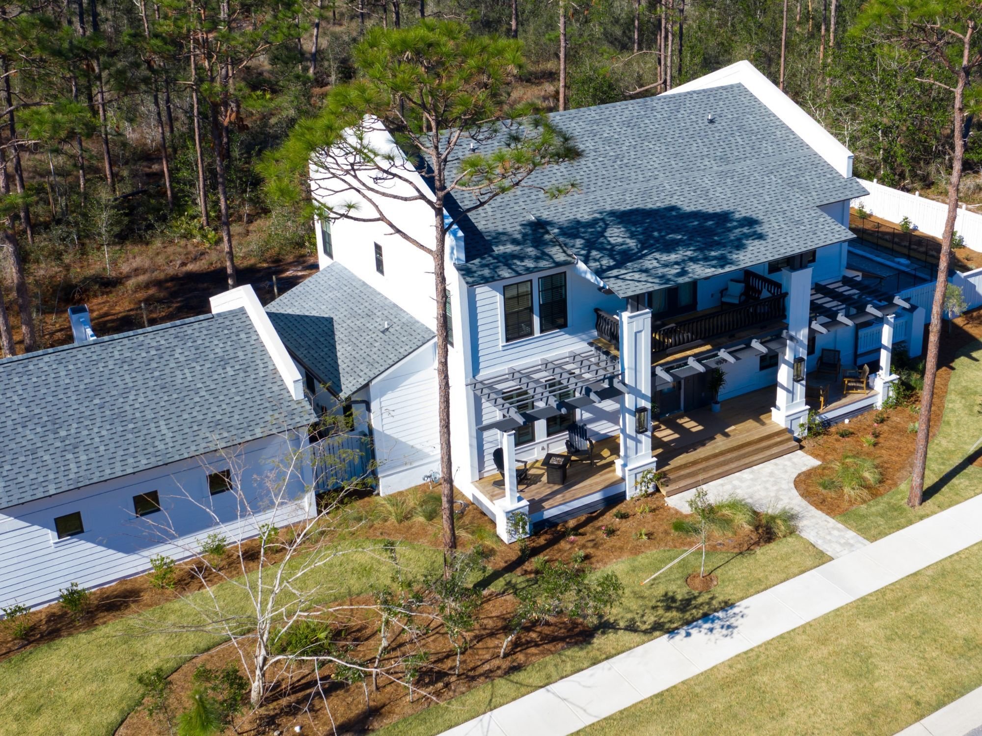 Aerial view of a Leeward custom home with Florida vernacular architecture, a large garage, and a pool by Urban Infill in Pensaco
