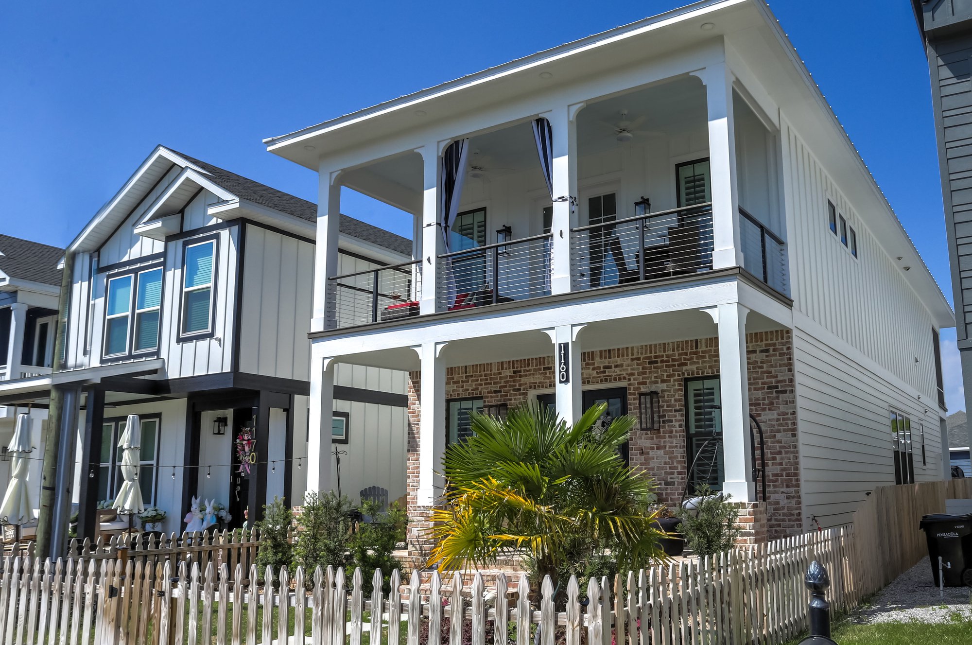 Front of a custom home with pillars and a second-story deck and fenced yard by Urban Infill Corporation