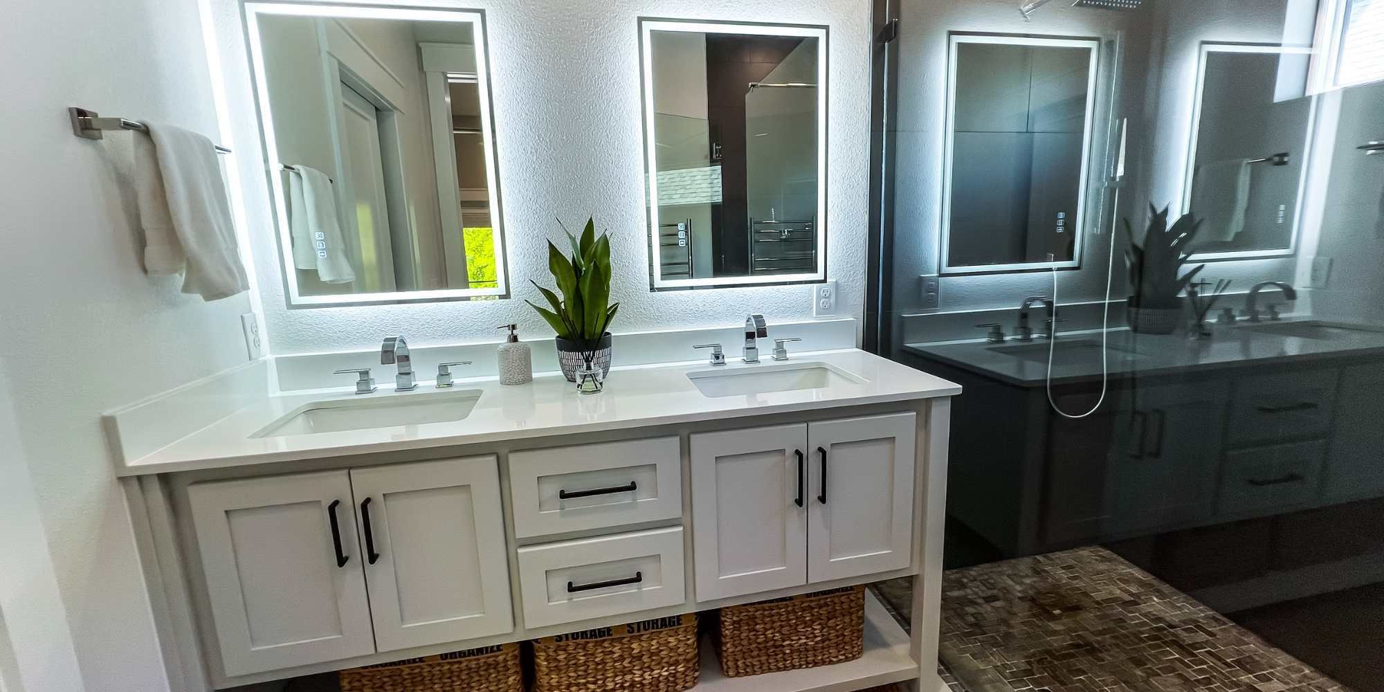 Ambient back-lit mirror lighting with a dual-sink vanity in a custom home by Urban Infill in Pensacola, FL