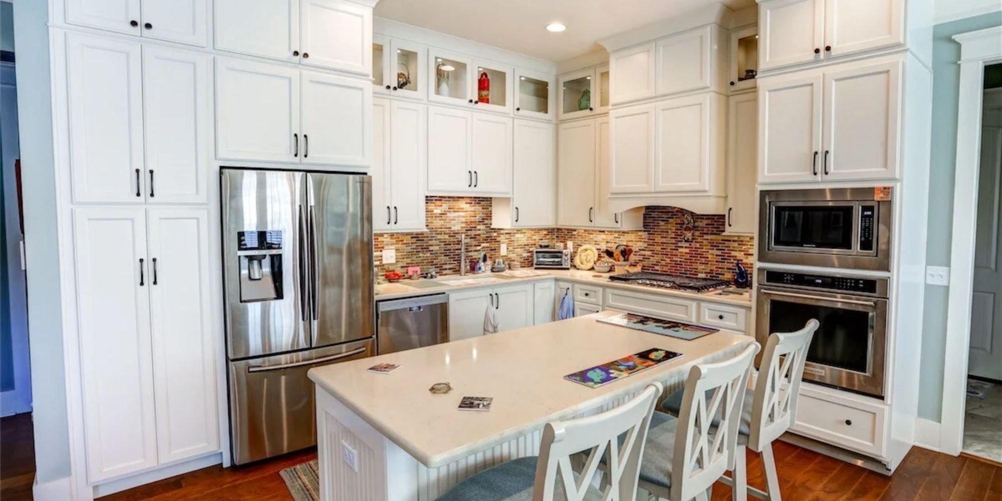 Light-filled kitchen remodel with glass display cabinets and sleek hardware by Urban Infill Company