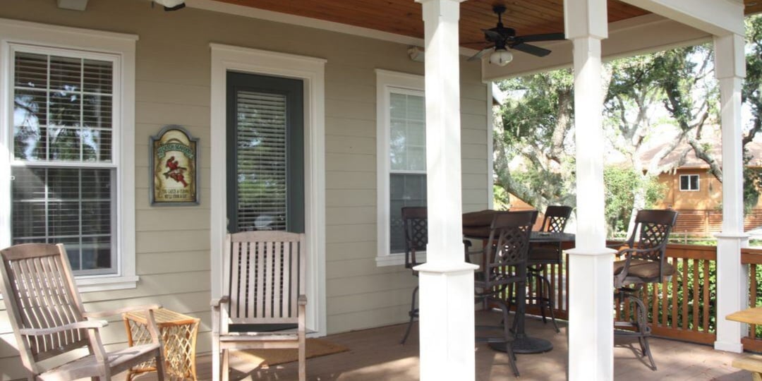Cozy screened porch in Pensacola custom home by Urban Infill, featuring rocking chairs and bar seating