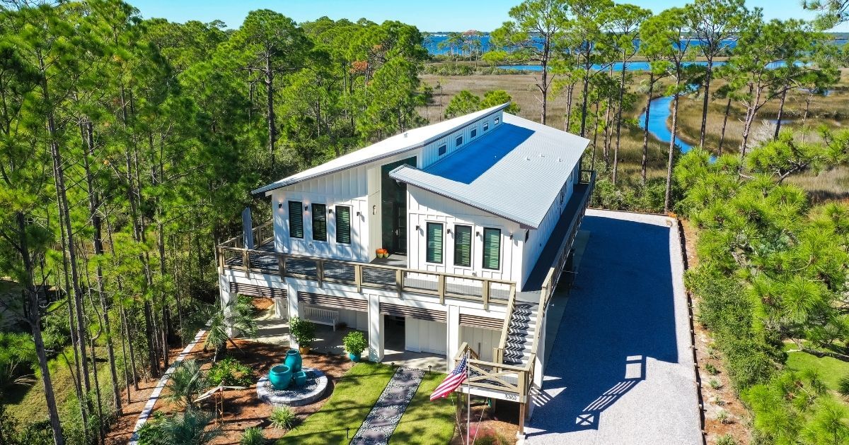 Custom home built on a piling foundation with a wraparound porch and unique roofline by Urban Infill in Pensacola, FL.