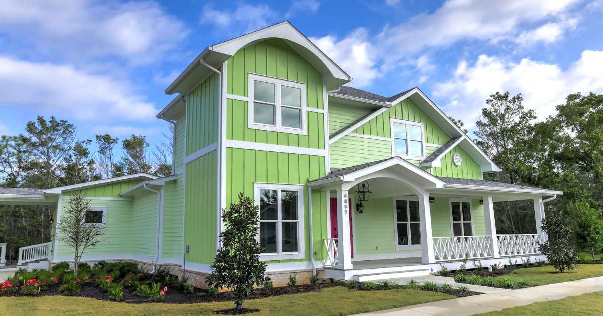 A remodeled home in Pensacola with a covered porch and bright green exterior by Urban Infill