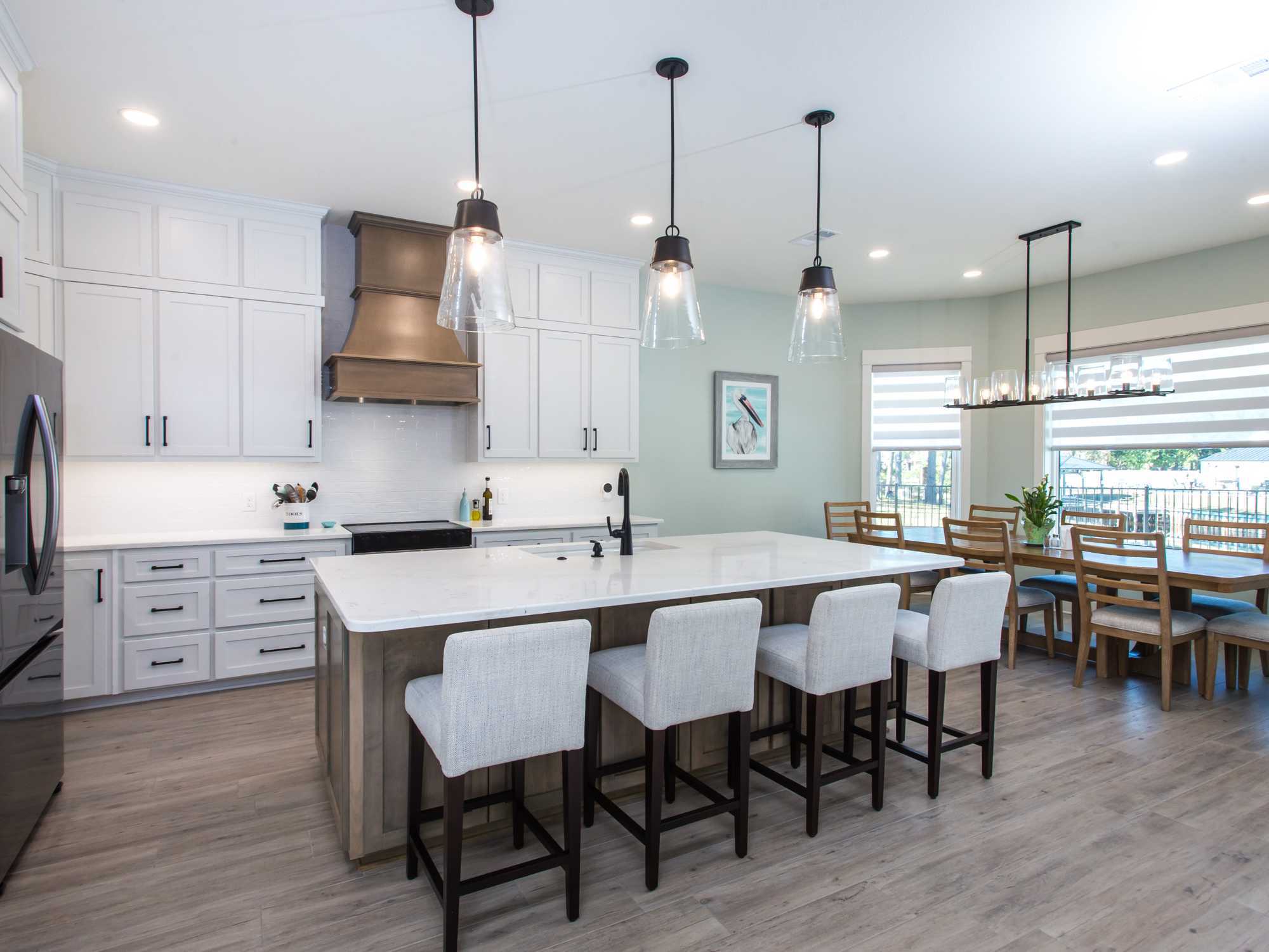 Image of kitchen remodel with large island, white cabinetry, and pendant lighting in Pensacola, FL by Urban Infill